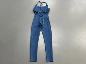 Detailansicht des tiefblauen Yoga-Jumpsuits mit Cross-Back-Design auf grauem Boden