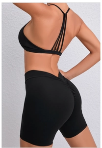 Detail of cross-strap sports bra and high-waist yoga shorts with ruched booty lifting
