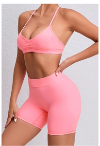 Detail showing neon pink yoga set with V-neck sports bra and high-waisted shorts