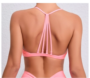 Détail du soutien-gorge de yoga rose corail avec sangles multiples croisées dans le dos