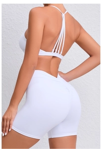 Close-up of white yoga set featuring cross-strap back and ruched scrunch butt shorts