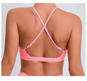 Détail d'un soutien-gorge de sport rose corail avec bretelles croisées et boucles métal