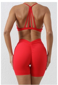Detail view of red yoga set featuring cross back sports bra and scrunch high waist shorts