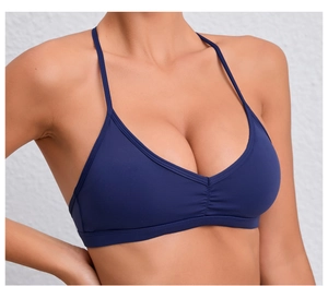 Détail du soutien-gorge de yoga bleu marine avec bretelles fines et design plissé sur le devant