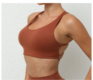 Side view detail of breathable rust red sports bra with wide straps and seamless finish