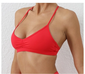 Détail latéral d'un soutien-gorge de yoga rouge à fines bretelles et décolleté plissé