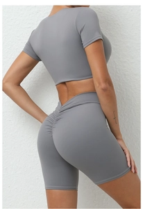 Detail eines grauen Yoga-Sets mit Ruched-Shorts und figurbetontem Crop-T-Shirt