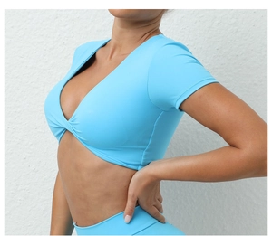 Primer plano de top corto de yoga azul claro con cuello en V y detalle de nudo frontal