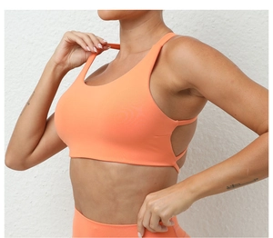 Side view of woman in bright orange yoga sports bra and high waisted leggings set