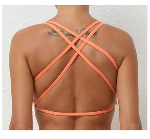 Detail view of vibrant orange yoga bra with stylish cross-back straps and elastic fabric