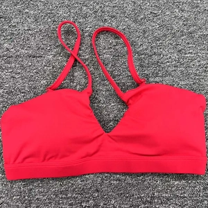 Brassière de sport rouge avec col en V et bretelles croisées sur fond sombre texturé