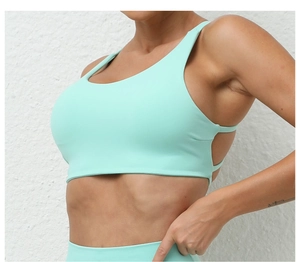 Detail of mint green breathable sports bra featuring side cross straps and open back design