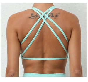 Close-up of mint green sports bra featuring a strappy criss-cross back design for women