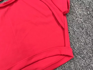 Detailed close-up of side seams and hem on a red quick-dry athletic yoga top