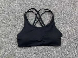 Detailed flat lay of black quick-dry sports bra with a cross-back strap design on grey rug