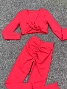 Ensemble de yoga rouge avec haut à manches longues torsadé et legging effet galbant fessier