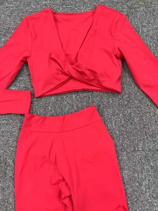 Détail à plat d'un ensemble de yoga rouge à manches longues et col en V sur un tapis