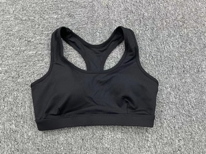Vue à plat d'une brassière de sport noire avec dos croisé sur surface grise