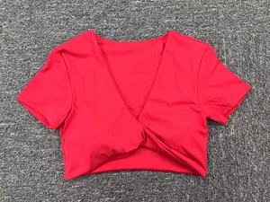 Detalle de crop top rojo con cuello en V y nudo cruzado en la parte frontal para fitness