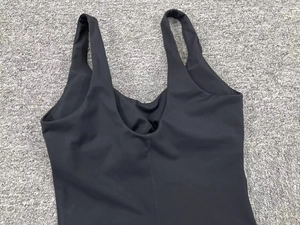 Flat lay detail of black yoga bodysuit showing high-elastic fabric and U-back stitching