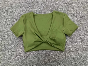 Detalle de un crop top de yoga verde con cuello en V y diseño de nudo en el bajo