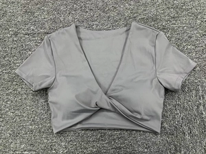 Detalle de top corto gris para yoga con cuello en V, dobladillo anudado y tela elástica