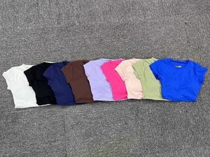 Vista piatta di nove top da yoga a compressione in vari colori su sfondo testurizzato