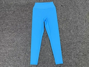 Détail du pantalon de yoga taille haute bleu clair sur un fond gris texturé élégant