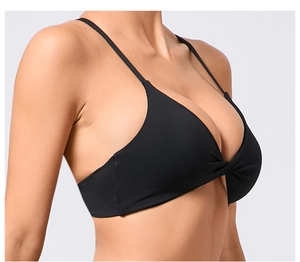 Détail du design torsadé à l'avant et du tissu élastique de ce soutien-gorge de sport noir