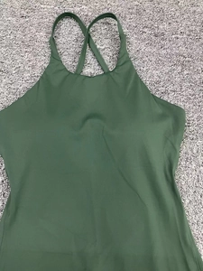 Detail showing cross-back strap design and deep green matte fabric of the yoga jumpsuit
