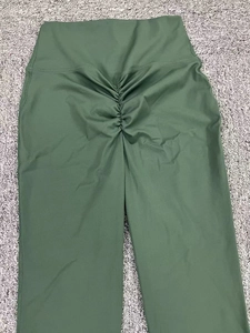 Détail du pantalon de yoga taille haute vert foncé avec effet galbant sur les fessiers