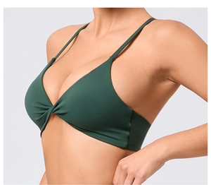 Détail d'un soutien-gorge de yoga vert foncé avec nœud torsadé et bretelles fines