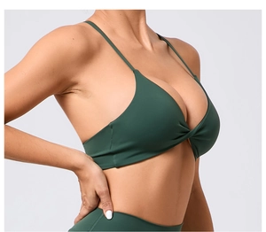 Détail de la brassière de yoga vert foncé avec fines bretelles et nœud torsadé à l'avant
