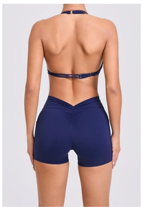 Rear view of dark blue yoga set showing ruched booty shorts and halter top with metal ring