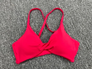 Détail des bretelles croisées et texture du tissu rose rouge du soutien-gorge de yoga
