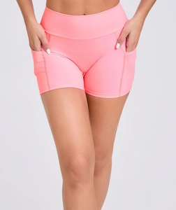 Detail showing high-waisted yoga shorts in coral pink with functional side pockets