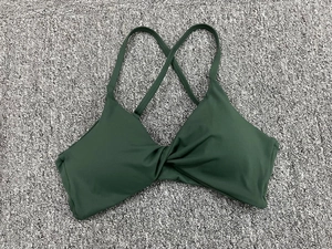 Détail du soutien-gorge de sport vert foncé avec nœud avant et bretelles croisées