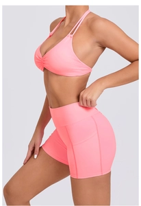 Detail view of pink high-waisted yoga shorts with side pocket and racerback sports bra