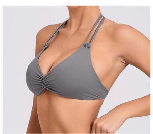 Dettaglio del top yoga grigio scuro con doppie spalline regolabili e design a pieghe sul petto