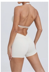 Detail of oat-colored scrunch butt fitness shorts and open back yoga top with V-cut waist