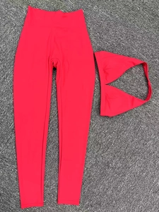 Ensemble soutien-gorge de sport rouge et legging de yoga taille haute posé sur un tapis