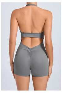 Back view of gray backless yoga bodysuit with halter neck and ruched detail on shorts
