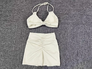 Detail of cream yoga set showing halter neck top with rings and ruched mini skirt