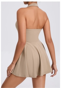 Back view of beige backless sports dress showing halter neck and pleated A-line skirt