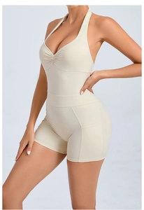 Detail view of the open-back halter yoga romper with side pockets in beige