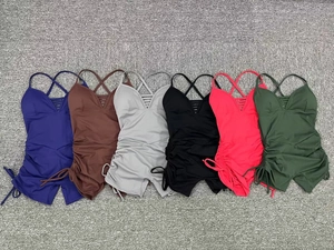 Flat lay of six colorful yoga bodysuits with side drawstring details on a neutral background