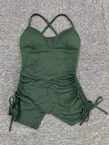 Flat lay detail of dark green yoga bodysuit with side ruching and crisscross back straps