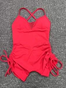 Detail of red hollowed-out yoga bodysuit with side drawstrings and crisscross straps