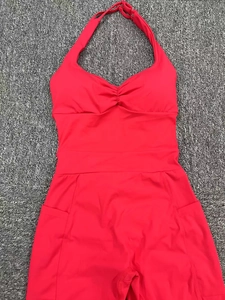 Flat lay of red halter yoga jumpsuit featuring side pockets and ruched chest detail