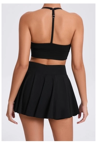 Detail view of the black sports bra back design and pleated tennis skirt set